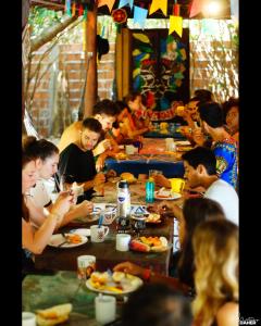a group of people sitting at a table eating food at Lagarto Na Banana Hostel in Pipa