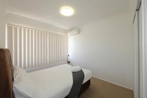 Un dormitorio pequeño con una cama y una ventana. en Alexandra Apartments, en Bundaberg