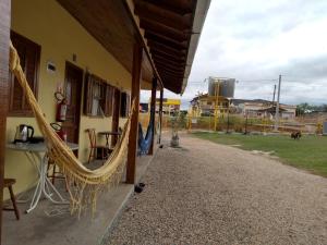 a patio with a table and a hammock next to a house at Pousada Balen in Pântano Grande