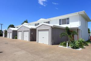 a white house with a row of garage at Alexandra Apartments in Bundaberg