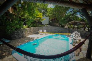 a swimming pool with a hammock in a backyard at Casa Atalaia in Pipa