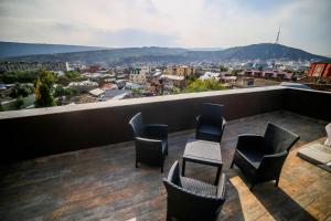 a balcony with chairs and tables and a view of a city at Boutique Hotel Mimino in Tbilisi City