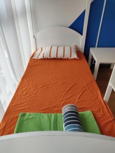 uma pequena cama num quarto com um colchão laranja em SkyBed Over The Sky Hostel @Regalia Suites & Residences KL em Kuala Lumpur