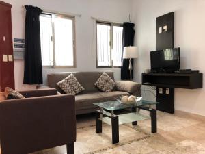 a living room with a couch and a television at Lilas del Mar Apartments in Playa del Carmen