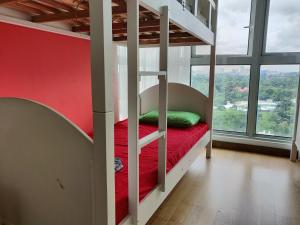 SkyBed Over The Sky Hostel @Regalia Suites & Residences KL في كوالالمبور: سرير بطابقين في غرفة ذات جدار احمر