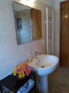 La salle de bains est pourvue d'un lavabo, d'un miroir et d'une table fleurie. dans l'établissement Il Casaletto, à Acquasparta