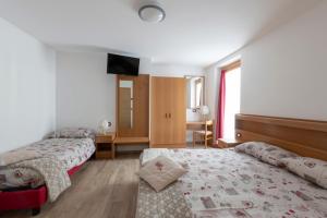 a hotel room with two beds and a television at Appartamento Patrizia e Franco in Commezzadura
