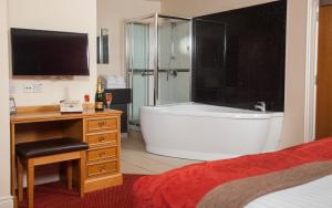a bath room with a tub and a television at Adelphi Portrush in Portrush