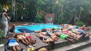 a group of people laying around a swimming pool at Lagarto Na Banana Hostel in Pipa