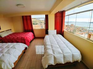 two beds in a room with a large window at Wisny Inn in Puno