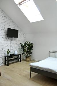 ein Schlafzimmer mit einem Bett und einem TV an einer weißen Ziegelwand in der Unterkunft Studio apartman Trešnjevka in Zagreb