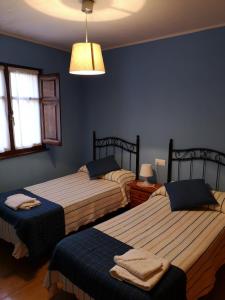 two beds in a bedroom with blue walls at Casa Guela Niembro in Niembro