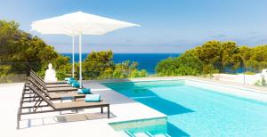 a swimming pool with chairs and an umbrella at White Villa Ibiza in San Jose