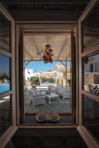 ein Fenster mit Blick auf eine Terrasse mit einem Tisch und Stühlen in der Unterkunft Kallisti Hotel in Folegandros Chora