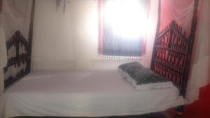 a small bedroom with a bed with a window at Wildebeeste Lamu in Lamu