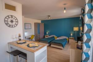 um quarto com duas camas e uma sala de estar com um relógio em Le cottage roannais em Roanne
