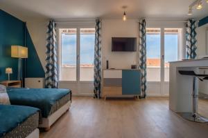 um quarto com uma cama, uma televisão e janelas em Le cottage roannais em Roanne
