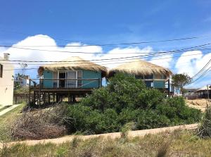 a house with a porch and a balcony with a roof at Casa Papaya in Punta Del Diablo