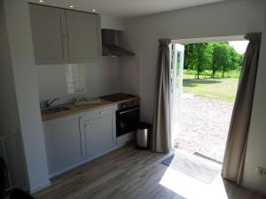 a kitchen with a sink and a door to a yard at B&B Het Rijkzicht in Groesbeek