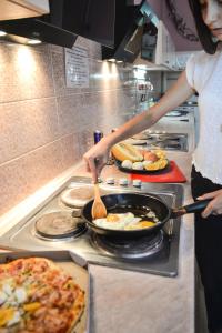 una mujer está cocinando comida en una sartén en una estufa en Vishnya Hostel, en Dnipro