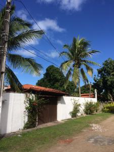 a house with a palm tree and a white wall at Casa de Arlete in Barra do Gil