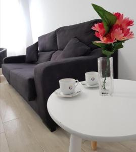 a living room with a couch and a white table with flowers at Málaga Alcolea in Málaga