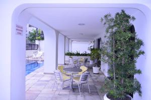 een patio met een tafel, stoelen en planten bij Ap Enseada Lado Praia Ar Cond Piscina Wi-Fi 500Mb in Guarujá