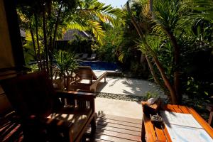 a patio with chairs and a table and a pool at Senang Villa by Ambassador in Gili Islands