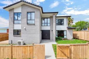 a white brick house with a wooden fence at Harmony Haven is close to airport in Auckland