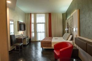 a hotel room with a bed and a red chair at Hotel Milano Navigli in Milan