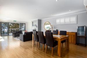 a dining room and living room with a table and chairs at The Edgewater on Greville in Sanctuary Point