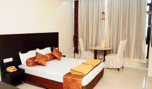 a bedroom with a bed and a table and a chair at Hotel Sri Kamal International in Solapur +9 photos