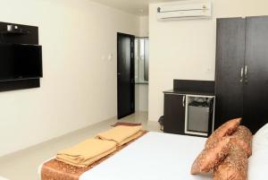 a bedroom with a large white bed and a kitchen at Hotel Sri Kamal International in Solapur