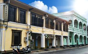 a row of buildings with a scooter parked on a street at Phuket Sunny Hostel in Phuket Town