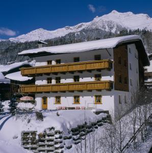 ein schneebedecktes Gebäude mit Bergen im Hintergrund in der Unterkunft Brunnenhof Apartments in Pettneu am Arlberg