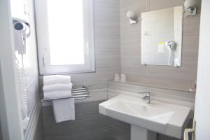 Baño blanco con lavabo y espejo en Hôtel Saint Antoine, en Angulema