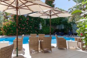 a patio with chairs and umbrellas next to a pool at Hotel Simius Playa in Villasimius