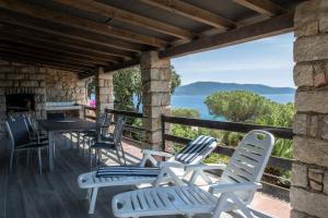 eine Terrasse mit Stühlen und Tischen sowie Meerblick in der Unterkunft VbyOnyx in Olmeto