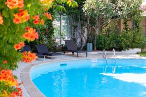 a swimming pool with two chairs and orange flowers at Hotel Simius Playa in Villasimius