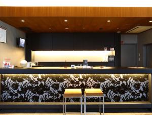 a kitchen with a counter with two stools in a room at Hotel Wing International Himeji in Himeji