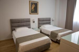 a hotel room with two beds and a table at Boutique Hotel Enia in Prato