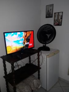 a television sitting on a stand with a fan at Recanto da Kaká in Ilha do Mel