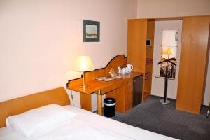 a bedroom with a bed and a desk with a lamp at Self Check-in Hotel Am Schottenpoint in Vienna
