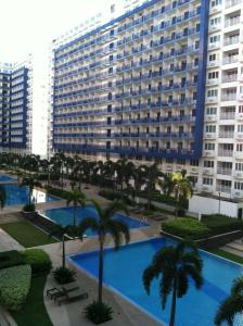 a large building with palm trees and a pool at Sea Residences Holiday Rentals in Manila