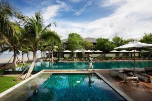 Ein Mann geht an einem Pool in einem Resort vorbei. in der Unterkunft Rest Detail Hotel Hua Hin in Hua Hin