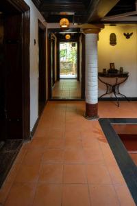 a hallway with a tile floor and a pillar at Kunnampath Heritage Nalukettu in Trichūr