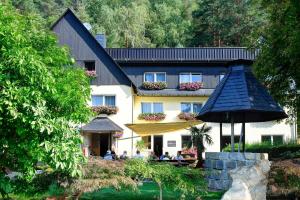 施塔特韦伦Pension Am Nationalpark的一座建筑,前面有人坐在伞下