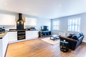 a living room with a black couch and a kitchen at Suite Life Serviced Apartments - Old Town in Swindon