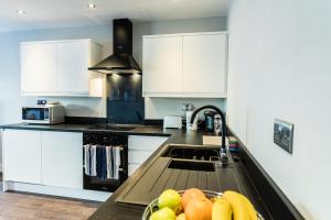 uma cozinha com armários brancos e um lavatório com fruta em Suite Life Serviced Apartments - Old Town em Swindon