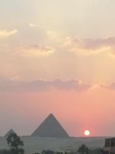 una puesta de sol sobre las pirámides en el cairo en Pyramids Power Inn en El Cairo